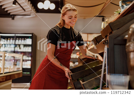 A Happy and Smiling Barista is Organizing Fresh Produce in a Trendy and Vibrant Cafe 119712342