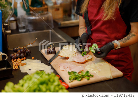 A skilled chef makes a fresh sandwich with chosen ingredients, ensuring hygiene and presentation 119712432