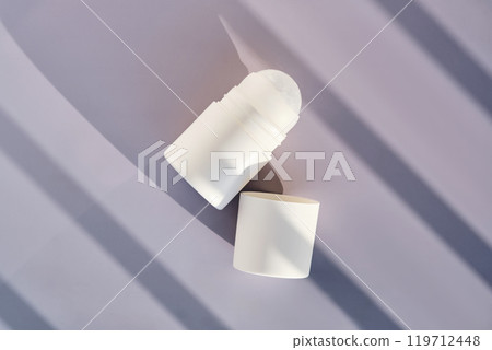 Roll-on deodorant on a purple background with shadow stripes. 119712448