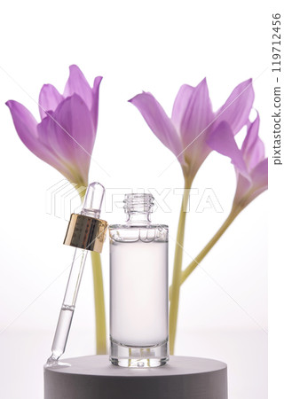 Serum bottle with dropper on light background with purple flowers. 119712456