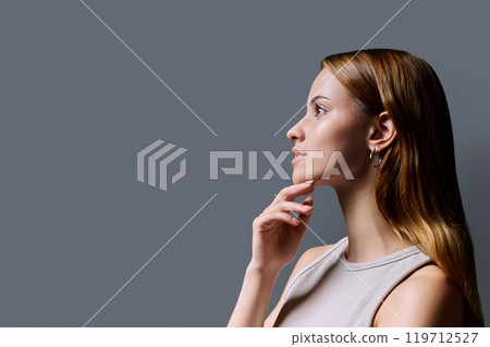 Headshot portrait in profile beautiful smiling young woman with red hair on gray background Headshot portrait in profile beautiful smiling young woman with red hair on gray background 119712527