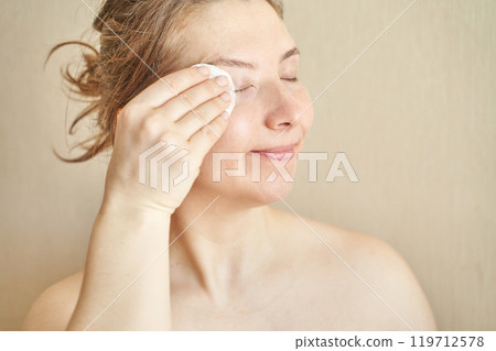 Woman cleansing face with cotton pad in morning skincare routine for fresh 119712578