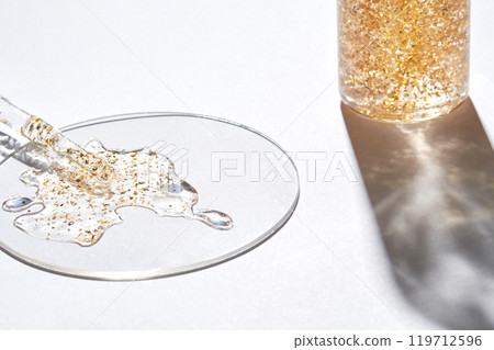 Golden liquid glitter in cosmetic bottle and petri dish on bright white Golden liquid glitter in cosmetic bottle and petri dish on bright white 119712596