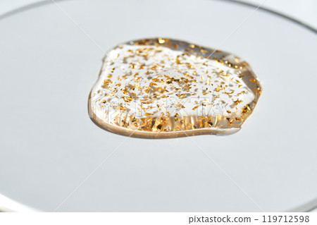 Luxe gold flake gel on white surface captures elegance and glamour in minimalist 119712598