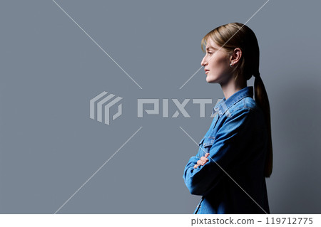 Profile view, confident young smiling teenage woman, copy space gray background 119712775