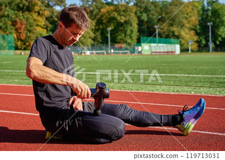 Athlete using handheld massage gun on leg after workout Athlete using handheld massage gun on leg after workout 119713031