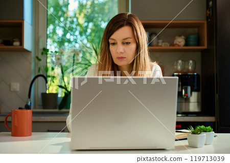 Freelance woman working on laptop at home desk Freelance woman working on laptop at home desk 119713039