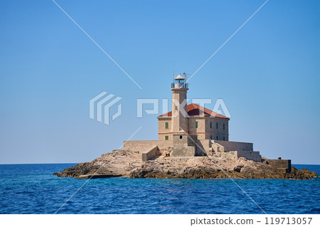 Seaside Lighthouse on Rocky Coast Under Clear Blue Sky 119713057