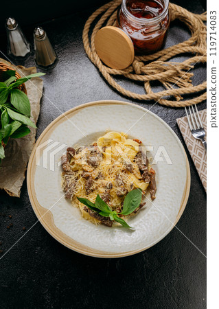 Creamy pasta with beef strips, Parmesan, basil, and sun-dried tomatoes, served in an elegant setting Creamy pasta with beef strips, Parmesan, basil, and sun-dried tomatoes, served in an elegant setting 119714083