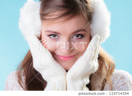 Happy woman in white earmuffs on blue Happy woman in white earmuffs on blue 119714304