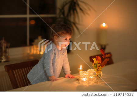 Child at home with candle and autumn decoration 119714522