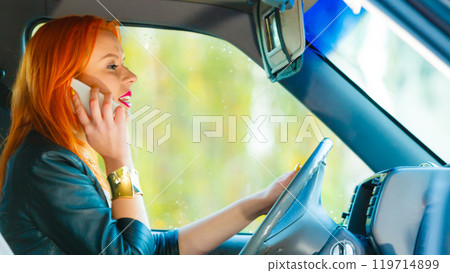 girl talking on mobile phone while driving the car. 119714899