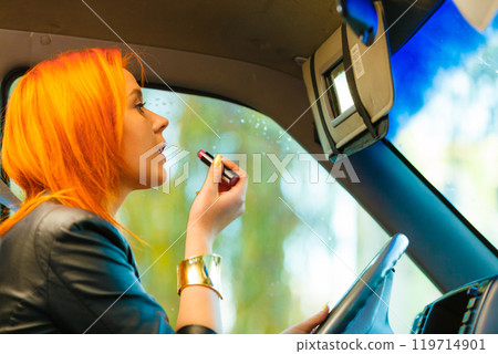 girl painting her lips doing makeup while driving the car. girl painting her lips doing makeup while driving the car. 119714901