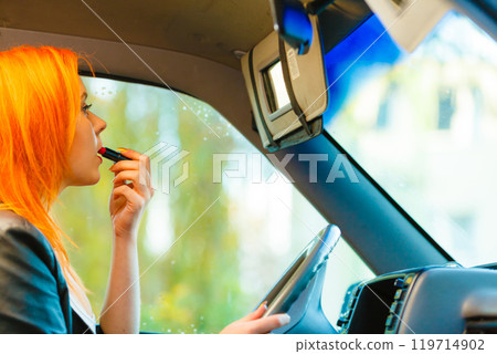 girl painting her lips doing makeup while driving the car. girl painting her lips doing makeup while driving the car. 119714902