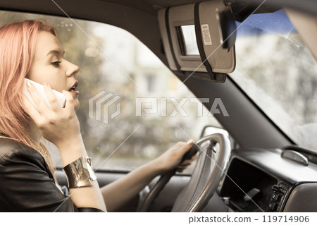 girl talking on mobile phone while driving the car. 119714906