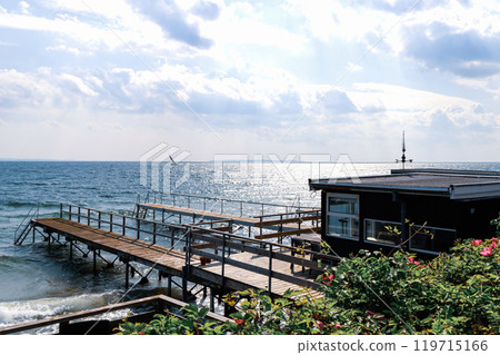 Beautiful seascape with sailing boat in the distance and pier Beautiful seascape with sailing boat in the distance and pier 119715166