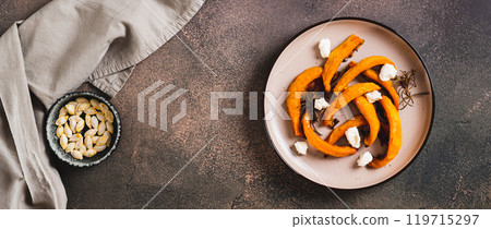 Appetizing pieces of sweet pumpkin baked with rosemary on a plate top view web banner Appetizing pieces of sweet pumpkin baked with rosemary on a plate top view web banner 119715297