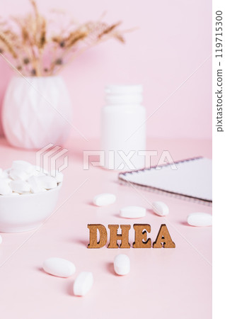 Hormonal supplement DHEA in tablets and a notebook on the table vertical view 119715300