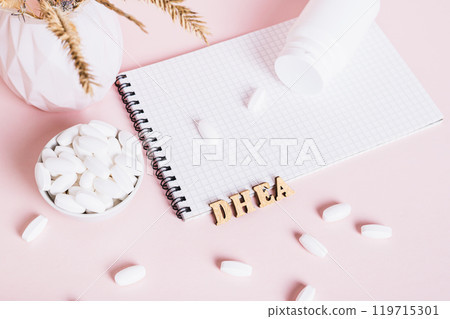 Hormonal supplements in a bowl, notebook and bottle on pink background 119715301
