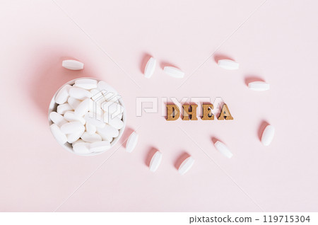 Hormonal supplement DHEA in tablets in a bowl on a pink background Hormonal supplement DHEA in tablets in a bowl on a pink background 119715304