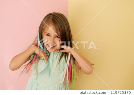 A sweet adorable girl adjusts her dyed bright colored hair. Artificial Hair Extensions 119715370