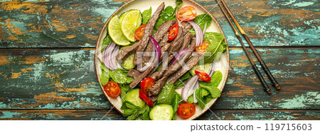Plate with traditional Thai beef salad with vegetables and mint top view served on rustic wooden background, healthy exotic asian meal 119715603