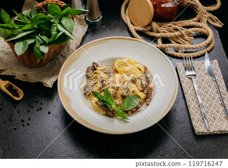Creamy pasta with beef strips, Parmesan, basil, and sun-dried tomatoes, served in an elegant setting Creamy pasta with beef strips, Parmesan, basil, and sun-dried tomatoes, served in an elegant setting 119716247