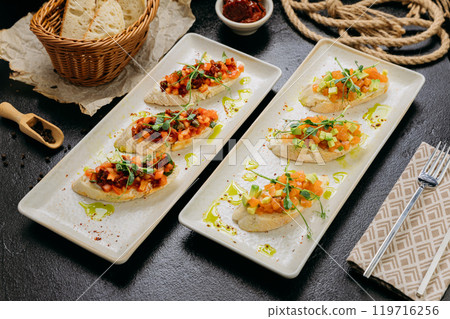 Assortment of gourmet bruschetta topped with salmon tartare, sun-dried tomatoes, avocado and herbs 119716256