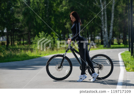 Caucasian woman riding a bike in a park. Caucasian woman riding a bike in a park. 119717109