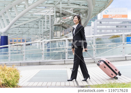 一位年輕的女商人拖著行李箱到名古屋出差 119717628