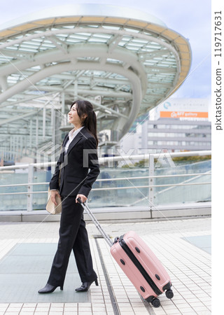 A young businesswoman pulling a suitcase on a business trip to Nagoya A young businesswoman pulling a suitcase on a business trip to Nagoya 119717631