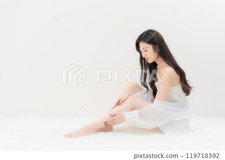 Beauty/Diet: A young woman sitting in a gymnastic position and worrying about her calves Beauty/Diet: A young woman sitting in a gymnastic position and worrying about her calves 119718392
