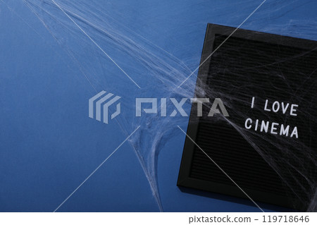 Black letter board with text and spider web on blue background, space for text 119718646
