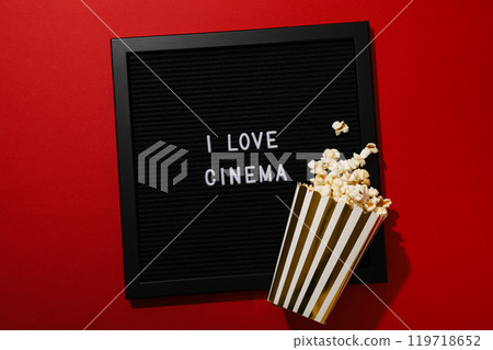 Black letter board and paper cup with popcorn on red background, top view 119718652