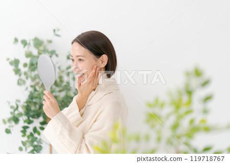 Middle-aged woman holding a hand mirror 119718767