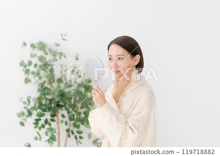 Middle-aged woman holding a hand mirror Middle-aged woman holding a hand mirror 119718882