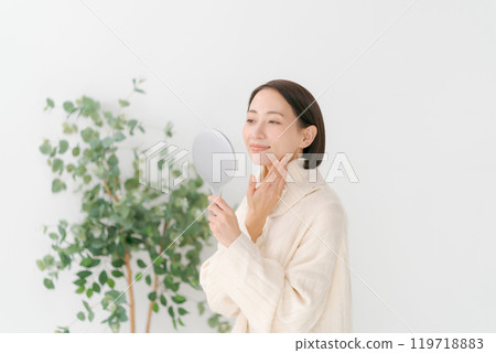 Middle-aged woman holding a hand mirror Middle-aged woman holding a hand mirror 119718883