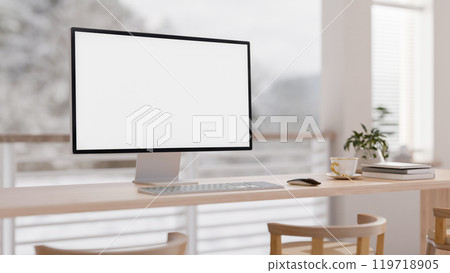 A close-up of a PC computer on a wooden table in a bright minimalist room with a view from a balcony 119718905