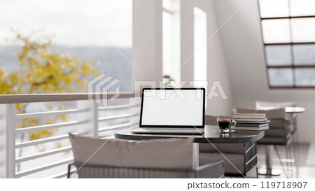 A laptop with a white screen mockup on a table in a modern coffee shop or hotel lounge patio. 119718907