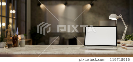 A laptop on a marble stone desk set against a blurred background of a living room at night. 119718916