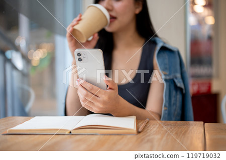 A close-up of a woman reading text messages on her smartphone while enjoying coffee in a coffee shop A close-up of a woman reading text messages on her smartphone while enjoying coffee in a coffee shop 119719032