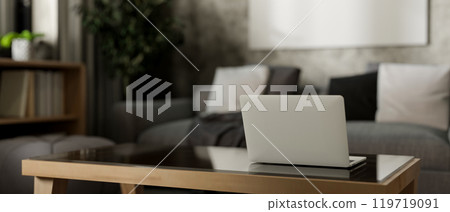 A back view of a laptop on a coffee table in a contemporary, loft living room. 119719091