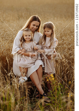 Young woman with two daughters in a wheat field during sunset. Young woman with two daughters in a wheat field during sunset. 119719982