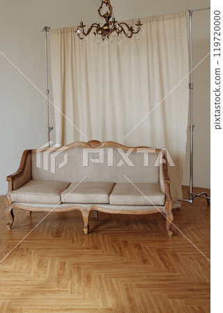 A wooden couch is sitting in front of a white curtain 119720000
