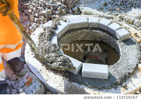 At concrete is being laid to anchor blocks completing upper edge of underground infrastructure manhole well At concrete is being laid to anchor blocks completing upper edge of underground infrastructure manhole well 119720167