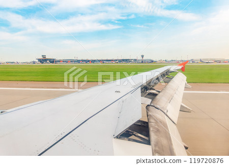 View of airplane wing, blue skies and green land during landing. Airplane window view. View of airplane wing, blue skies and green land during landing. Airplane window view. 119720876