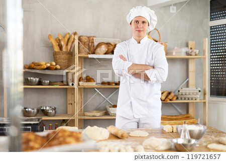 Portrait of young man baker smiling at camera posing during daily work in bakery 119721657