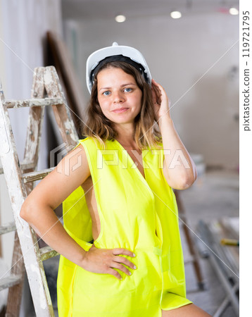 Tempting woman in yellow vest over naked body posing in construction site 119721795