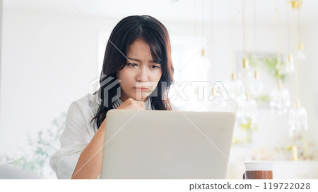 A woman worried while looking at a laptop A woman worried while looking at a laptop 119722028