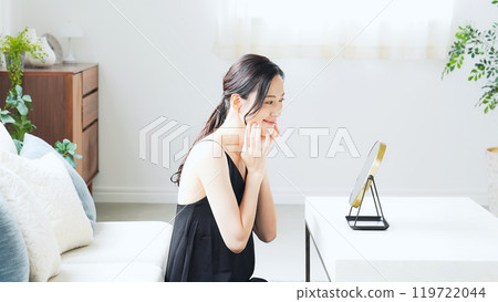 一個女人在室內照鏡子做皮膚護理 119722044
